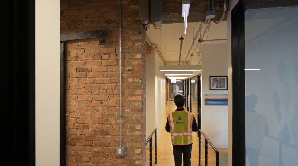 An operator walks a corridor wearing the helmet