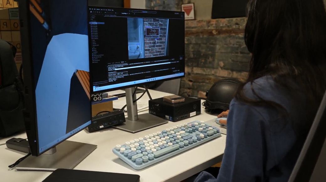 An engineer reviews analysis results at a desk next to the helmet