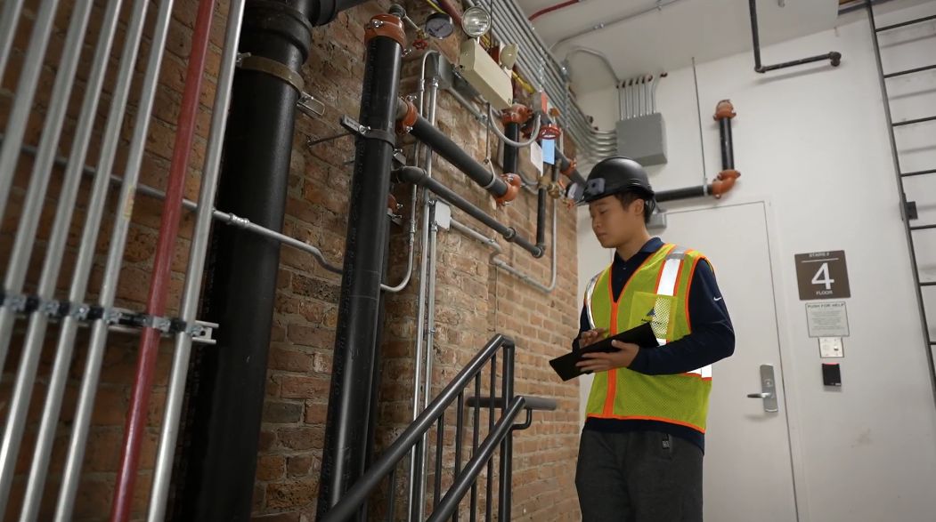 A superintendent wearing the helmet checks the tablet in a stairwell